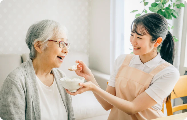 高齢者の食事を介助する介護職員の写真